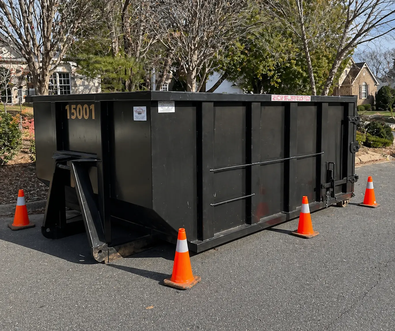 Large black dumpster on grassy field under cloudy sky