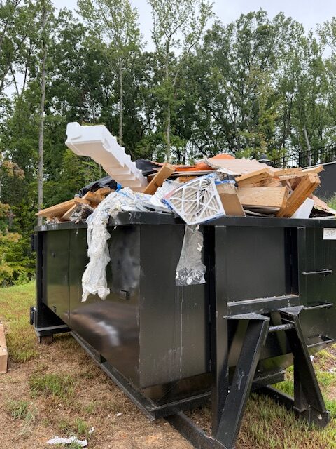 Dumpster filled with assorted debris including wood, cardboard, and plastic